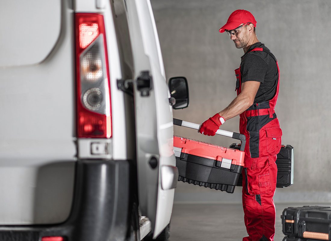 Business Insurance - Professional Contractor Wearing a Red Uniform and Hat Loads a Van With His Tools