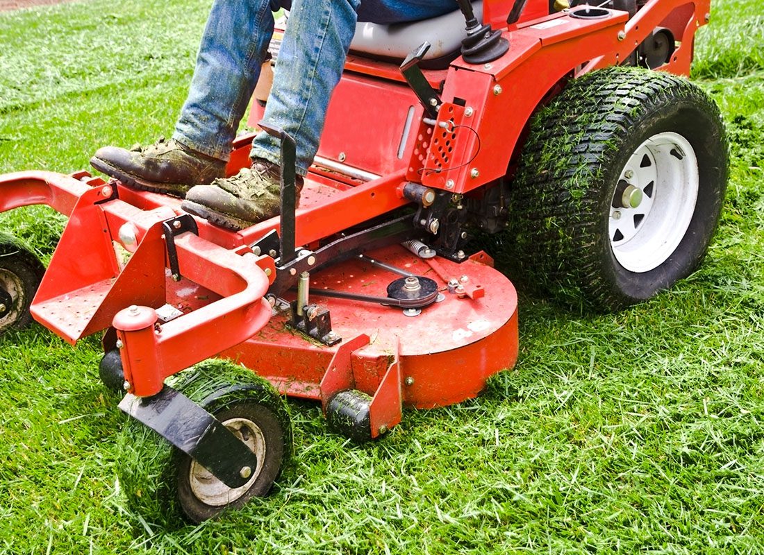 Insurance by Industry - Close-up of a Red Ride Along Lawnmower Cutting Grass